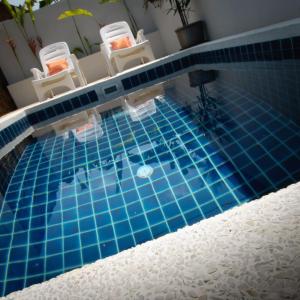 a swimming pool with two chairs and a table at Chalisa Villas Koh Tao in Koh Tao