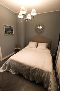 a bedroom with a bed with white sheets and a chandelier at ZE-VI HOME in Santa Flavia