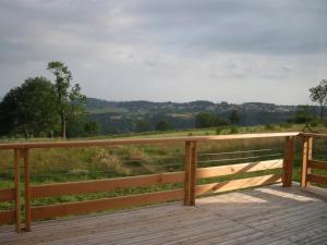 une terrasse en bois avec vue sur un champ dans l'établissement Auberge BRIASSOU, à Grazac