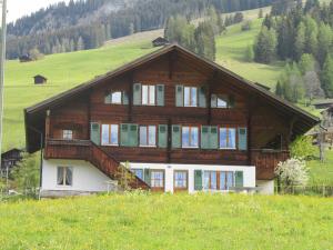 ein großes Holzhaus auf einem Hügel auf einem Feld in der Unterkunft Gutenbrunnenstrasse 94 in Lenk im Simmental