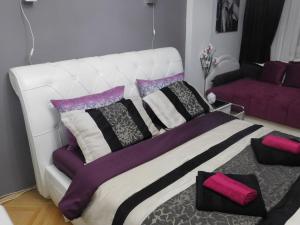 uma cama branca com almofadas roxas e pretas num quarto em Velvet Lux Apartment em Niš