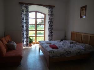 a bedroom with a bed and a window and a couch at Dvůr v Borovné in Borovná