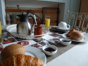 uma mesa com um pequeno-almoço de croissants, café e sumo de laranja em Le Petit Grenier em Bayeux