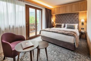 コルティーナ・ダンペッツォにあるホテル ラジャディーラ ＆ スパのベッドと椅子付きのホテルルーム