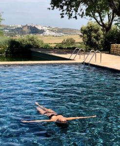 Una donna sdraiata sulla schiena in una piscina di Cortijo Bablou - Maison de vacances ad Arcos de la Frontera