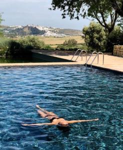 une femme qui se pose sur le dos dans une piscine dans l'établissement Cortijo Bablou - Maison de vacances, à Arcos de la Frontera