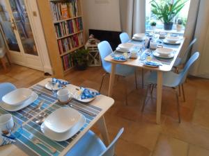 a table with blue chairs and white dishes on it at Maison Jonela in Châteauneuf-du-Faou