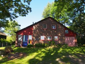 a red barn with a blue door in a yard at Haus am Deich in Kollmar