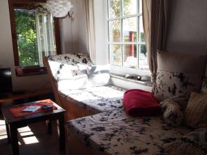 Zimmer mit Sofa, Tisch und Fenstern in der Unterkunft Haus am Deich in Kollmar