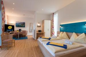 a hotel room with two beds and a living room at Barry Memle Directly at the Lake in Velden am Wörthersee