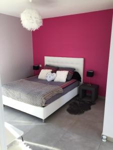 1 dormitorio con cama blanca y pared rosa en La chambre rose, en Mâcon