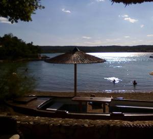 a beach with an umbrella and people in the water at Apartment Sun & Sea in Krk