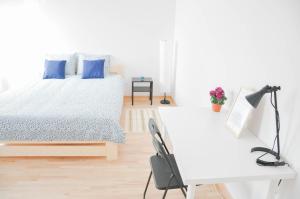 a white bedroom with a bed and a desk at HaLo Rooms City Centre in Warsaw