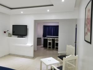 a white living room with a tv and a table at Esmeralda in Santo Domingo