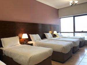 a hotel room with three beds with white sheets at Manazel Alaswaf Hotel in Al Madinah