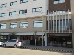 un coche blanco estacionado frente a un edificio en Nandó Apart Hotel en Cipolletti