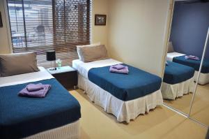 a room with two beds with mirrors and purple towels at TL Warmest Homestay in Gold Coast