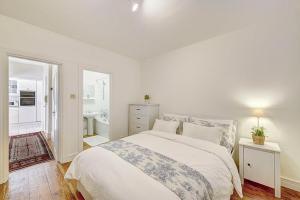 a white bedroom with a bed and a bathroom at Hampstead Stylish Apartment Brilliant Location in London