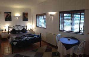 a bedroom with a bed and a table and windows at Tanglewood Gatwick Bed & Breakfast in Crawley