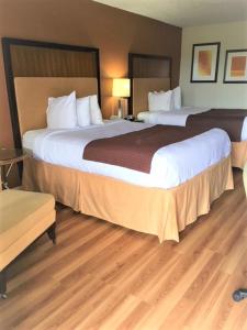twee grote bedden in een hotelkamer met houten vloeren bij Royal Inn in Sparta