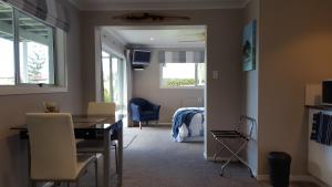 een woonkamer met een tafel en stoelen en een slaapkamer bij Bird Haven in Coromandel Town