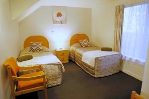 1 dormitorio con 2 camas, ventana y silla en Bush Inn Court Motel, en Christchurch