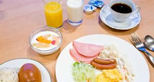 a wooden table with plates of breakfast food and drinks at Shiki Resort Prego Hayama in Hayama