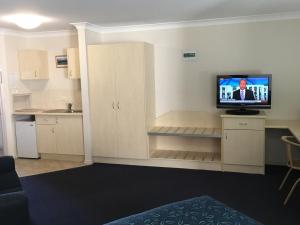a kitchen with a television and a refrigerator at Tuckerbox Motor Inn in Gundagai