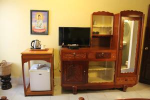 a room with a tv and a cabinet with a mirror at Seven Candles Guesthouse in Siem Reap