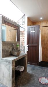 a bathroom with a sink and a wooden door at NamaStay in Ubud