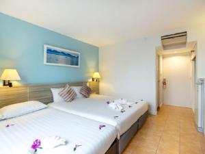 two beds in a hotel room with flowers on them at ON Hotel Phuket - SHA in Karon Beach