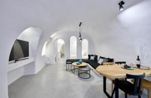 a living room with white walls and a table and chairs at Cave Suite Oia in Oia