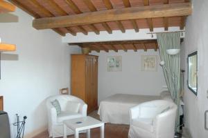 a bedroom with a bed and two white chairs at Montefili in Greve in Chianti