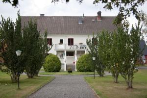 une grande maison blanche avec des arbres devant elle dans l'établissement Pensionat Klåvasten, à Skövde