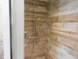 a shower in a bathroom with wooden walls at Chambres d'hôtes La Catounière in Fontainebleau