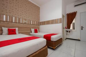 2 letti in camera con cuscini rossi di RedDoorz near Plaza Simpang Lima a Semarang