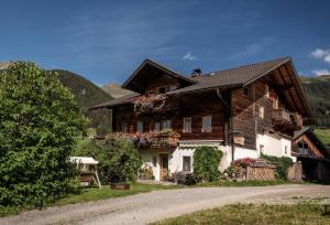 a large wooden house with flowers on the windows at Oberhabererhof in Santa Maddalena in Casies