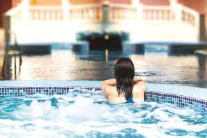 una mujer está sentada en una piscina en Hoar Cross Hall, en Newborough