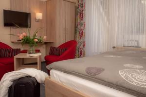 a hotel room with a bed and two red chairs at Pension Thieshof in Amelinghausen