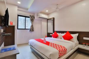 a bedroom with a large bed with red pillows at Hotel Sunrise in Ahmedabad