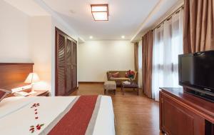 ein Hotelzimmer mit einem Bett und einem Flachbild-TV in der Unterkunft La Dolce Vita Hotel in Hanoi