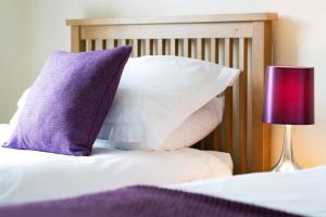 a bed with purple and white pillows and a lamp at BELLE VUE - SKIPTON in Skipton