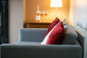 a couch with two red pillows on it at BELLE VUE - SKIPTON in Skipton