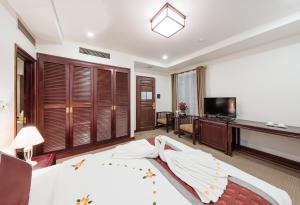 a bedroom with a bed and a desk and a television at La Dolce Vita Hotel in Hanoi