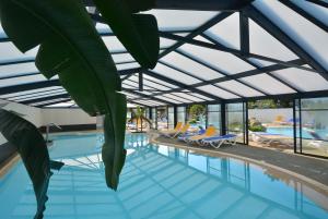 uma piscina com telhado de vidro e uma planta em Lebraz 3 Appartement em Saint-Lunaire