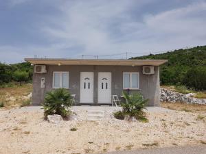 a small house with white doors in the desert at Studio Apartment Sanja 2 in Neum