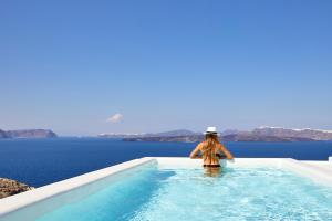 a woman standing in a swimming pool looking out over the ocean at Phos The Boutique in Akrotiri