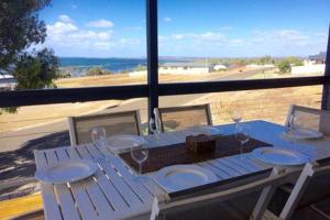 a white table with chairs and a view of the ocean at Bayview Beach House Apartment No 1 in Kingscote