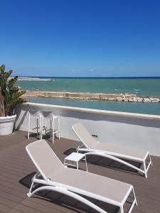 a group of chairs and tables on a deck with the ocean at MoMa B&B Molfetta Mare in Molfetta