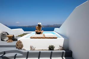 a woman sitting on a bench on a balcony overlooking the ocean at Phos The Boutique in Akrotiri